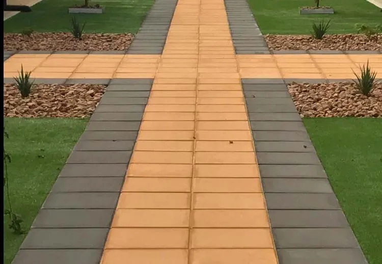 A paved path running between lawn and garden beds, with a contrasting brick strip laid down its centre